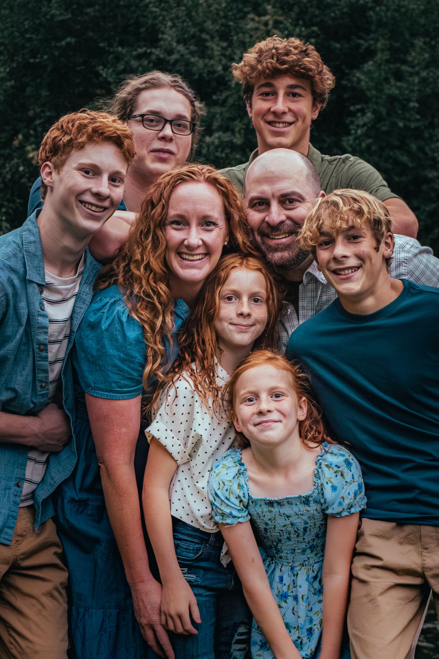 Group photo of people huddled together outdoors with natural lighting and dark background.