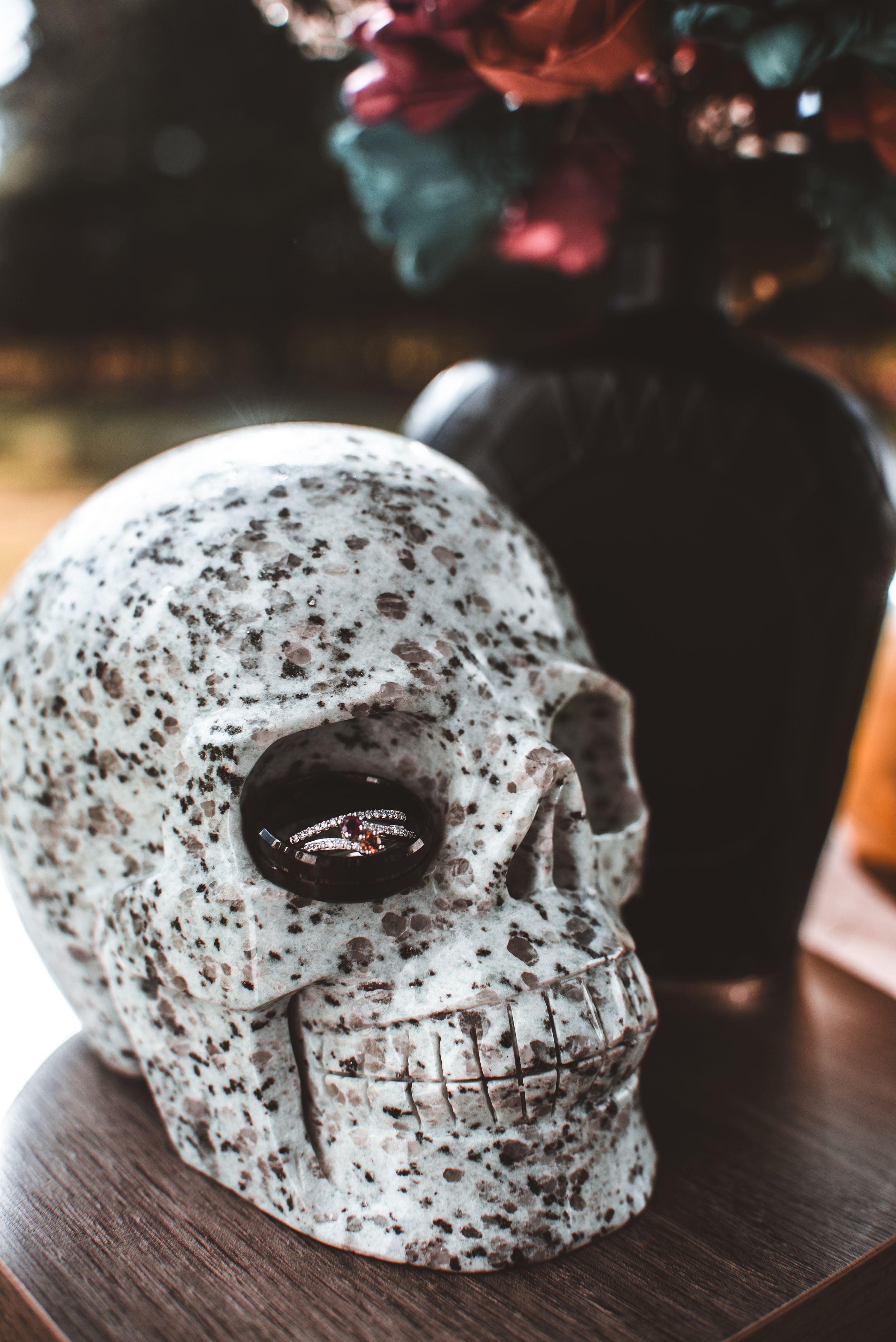 Decorative white speckled skull with wedding ring placed in eye socket for artistic photo.