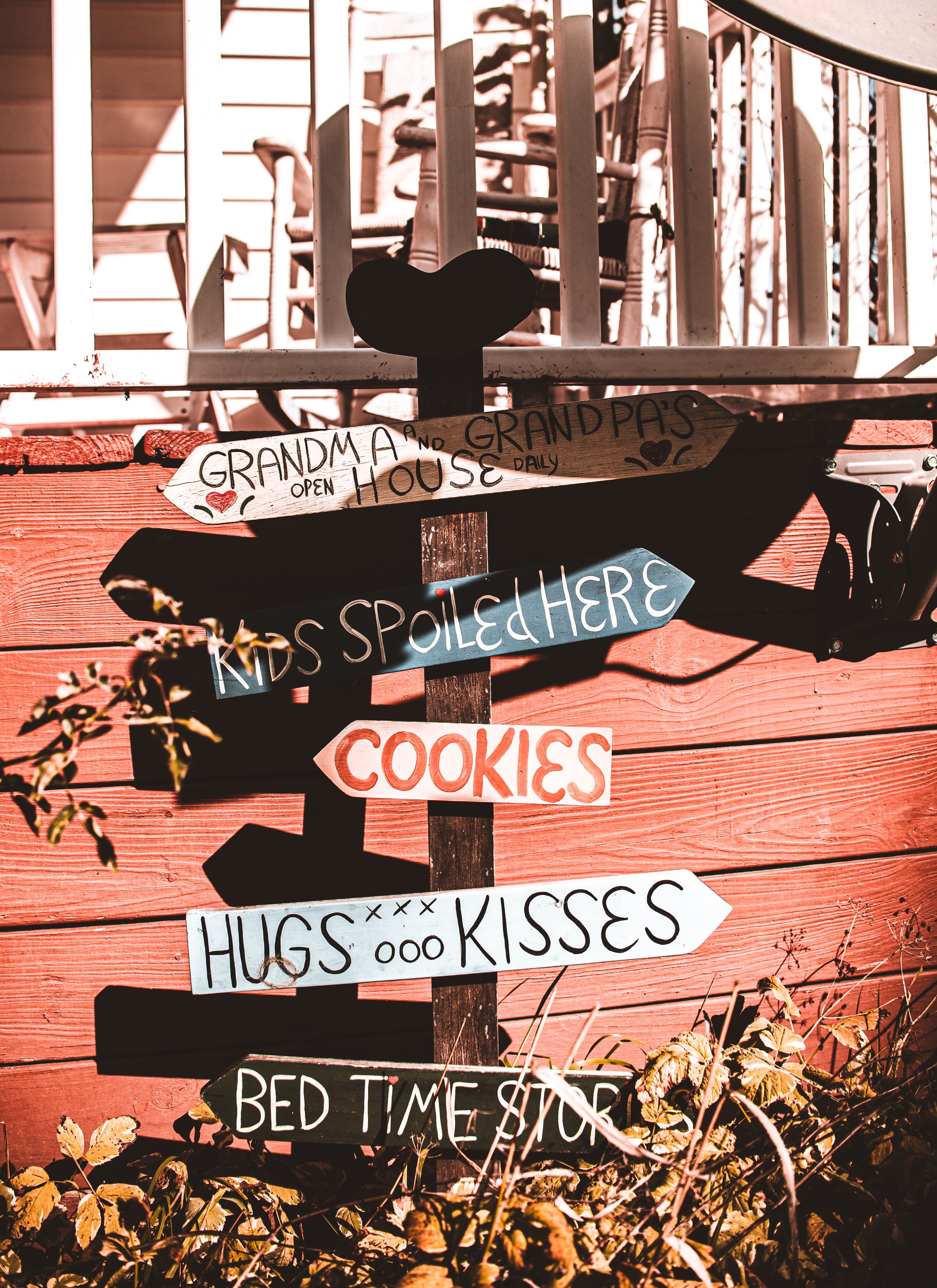 Charming rustic directional signs with phrases like 'Grandma's House' and 'Cookies' mounted on red wood.