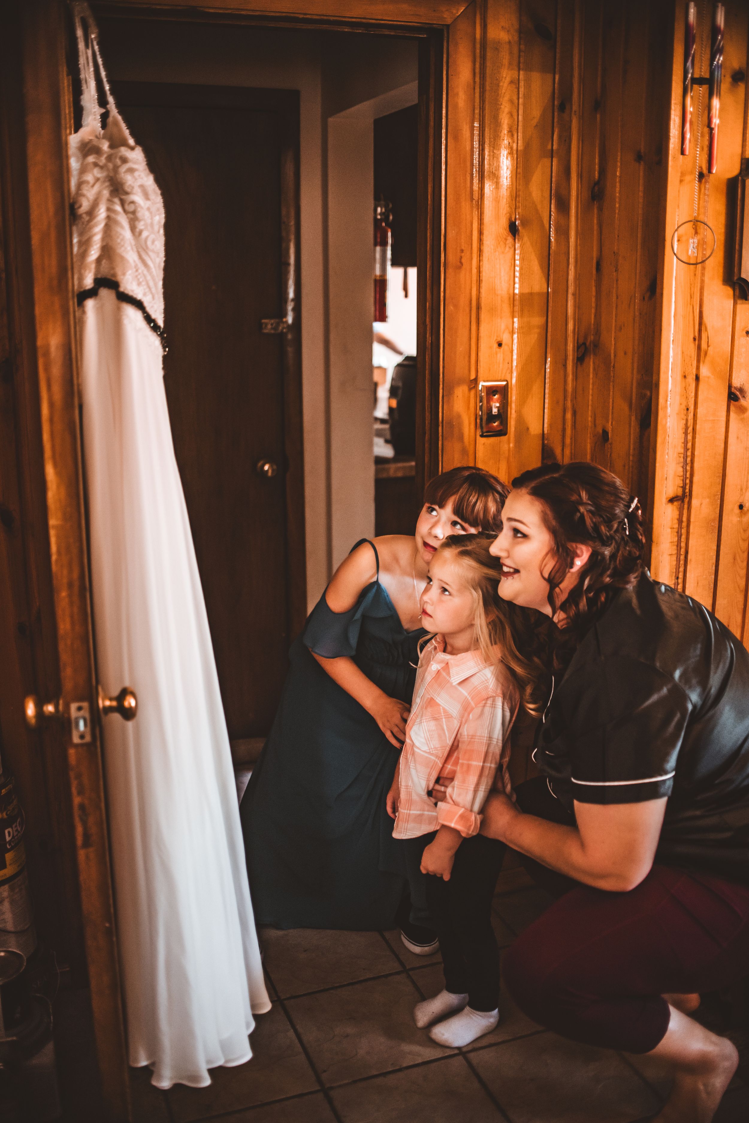 Wedding preparation scene with white dress hanging in rustic wood-paneled room.