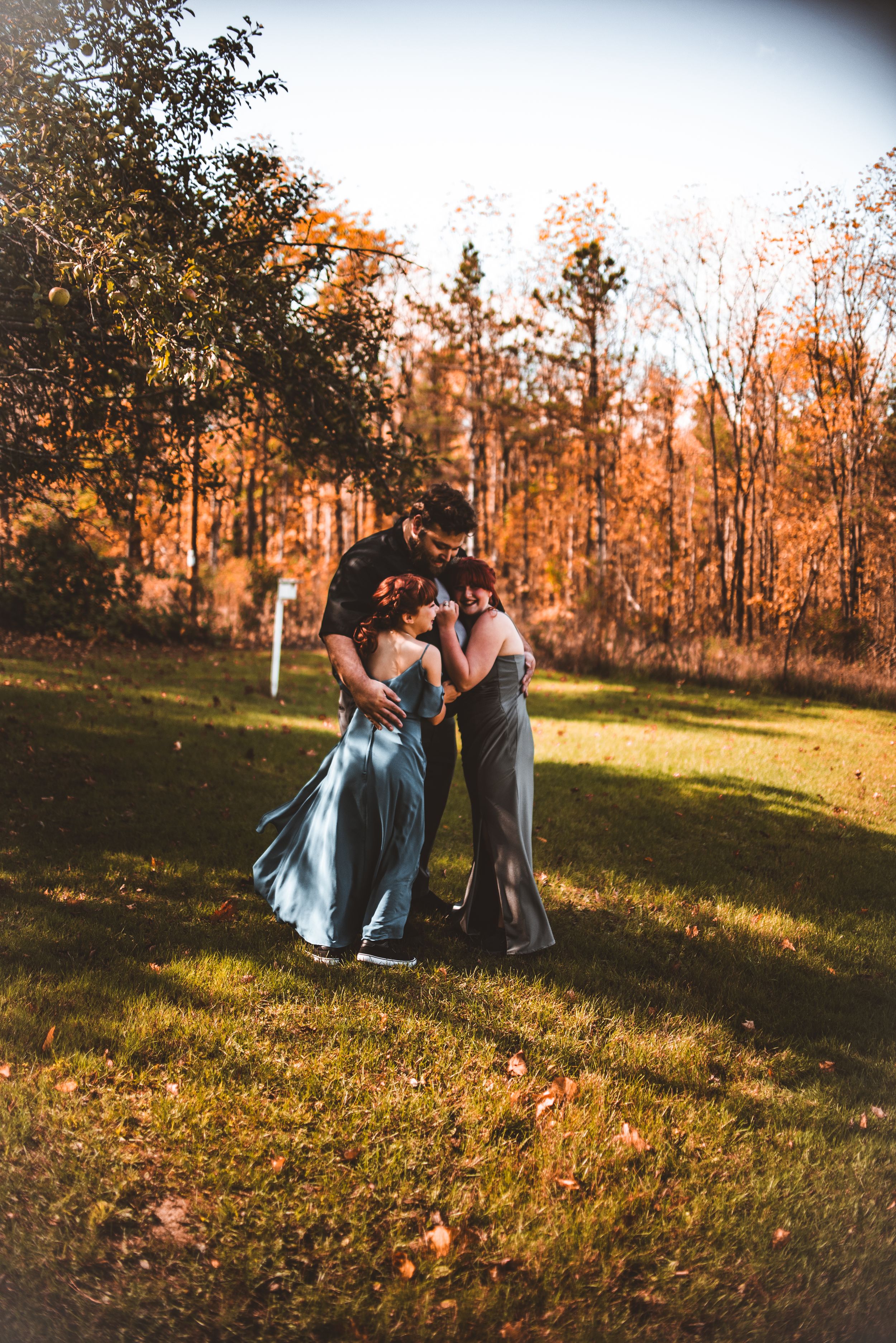 Two people in formal attire share an intimate dance at sunset in an autumn field.