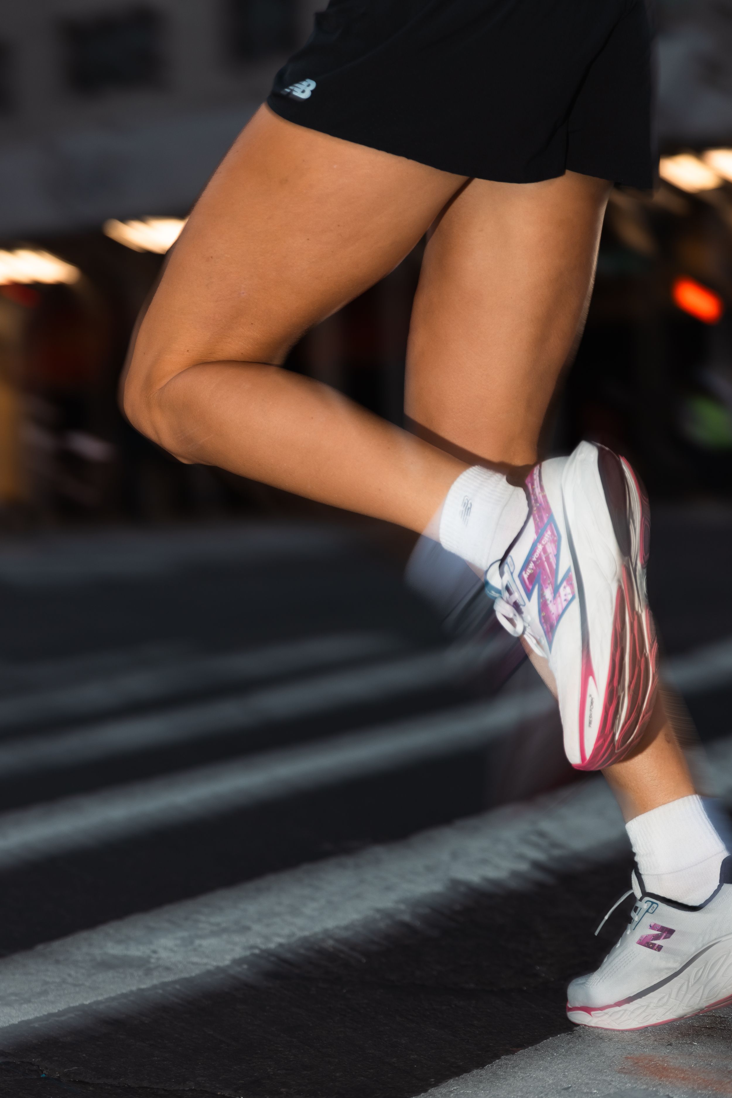 Close-up of legs wearing white and pink athletic sneakers mid-stride during a run.