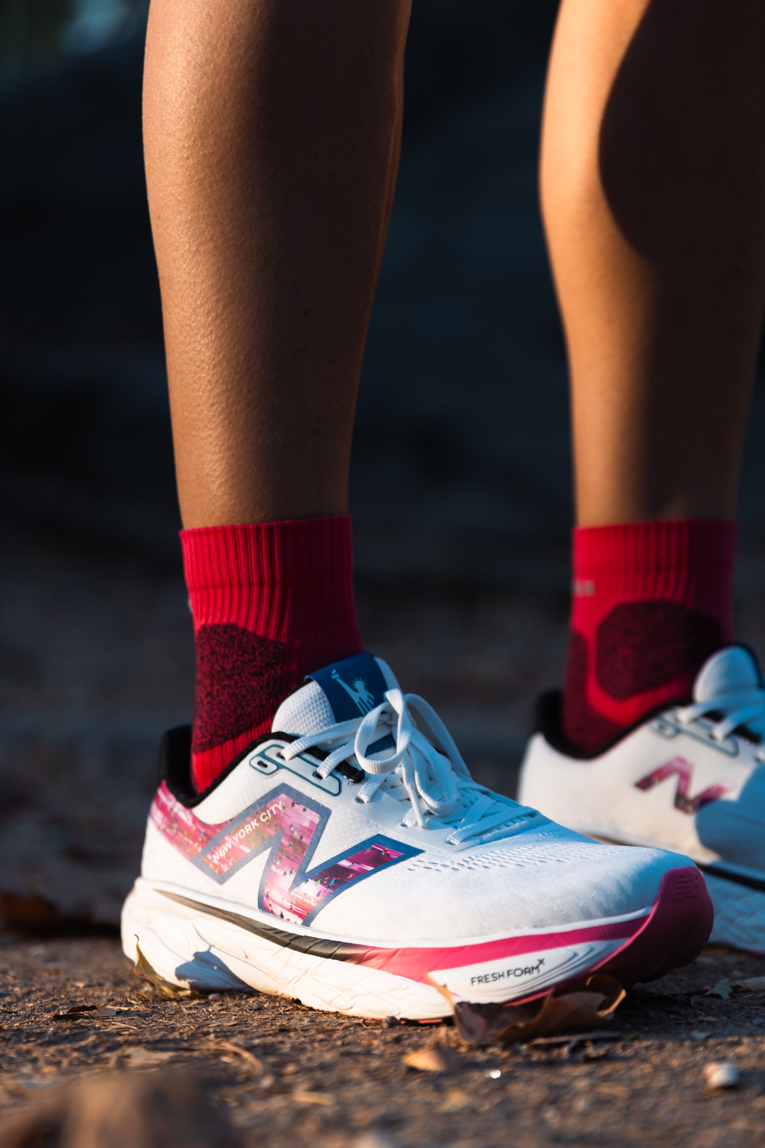 Close-up of running shoes with red socks on pavement in natural lighting.