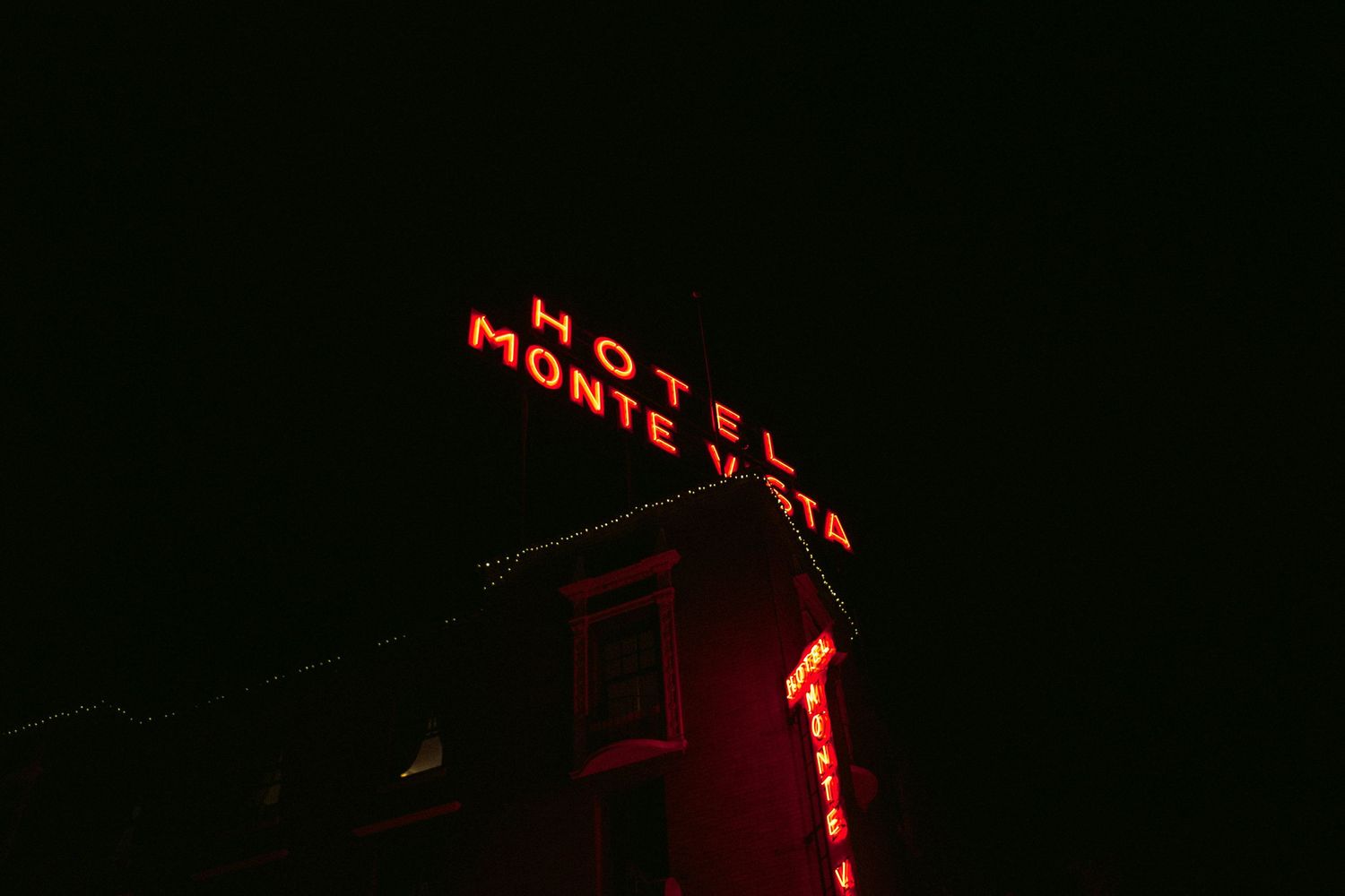 Red neon Hotel Monte Vista sign in Flagstaff glowing against the dark night sky.