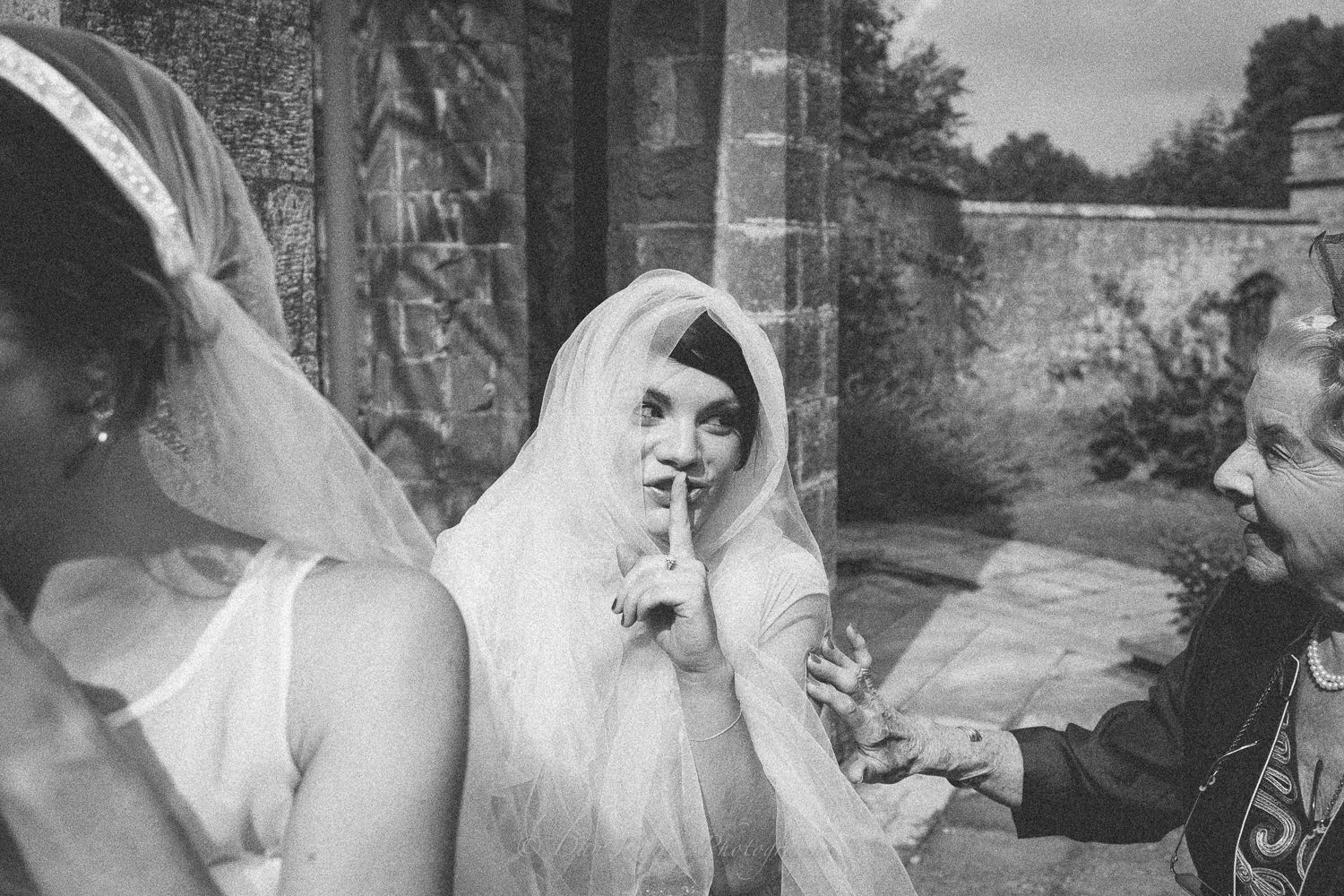 Reportage detail shot of bridesmaid hiding in the brides Weil during the wedding reception
