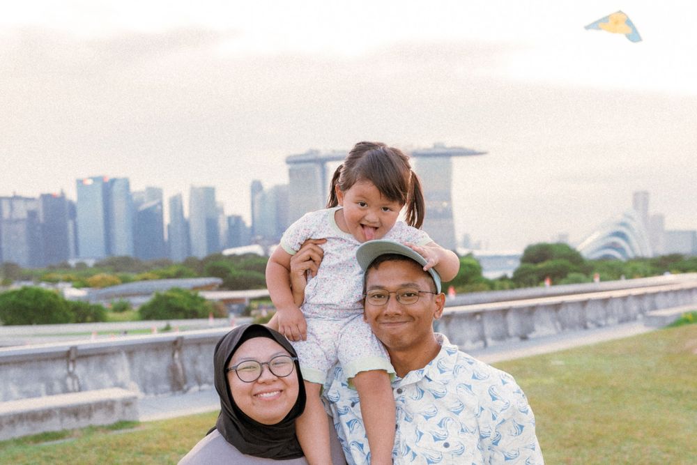 Family portrait with city skyline backdrop featuring Marina Bay Sands in Singapore.