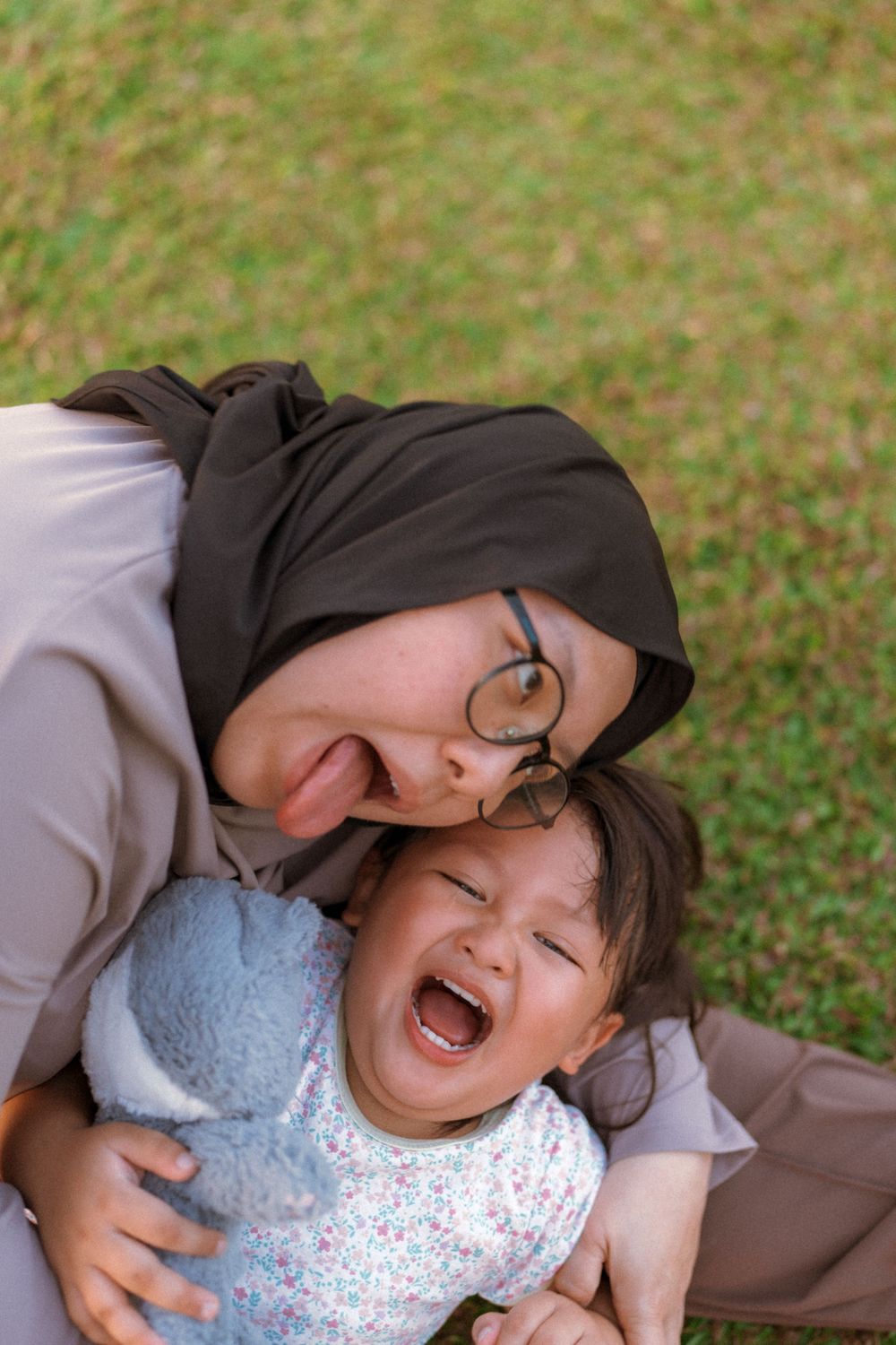 A joyful outdoor portrait capturing laughter and cuddles with a blue plush toy.