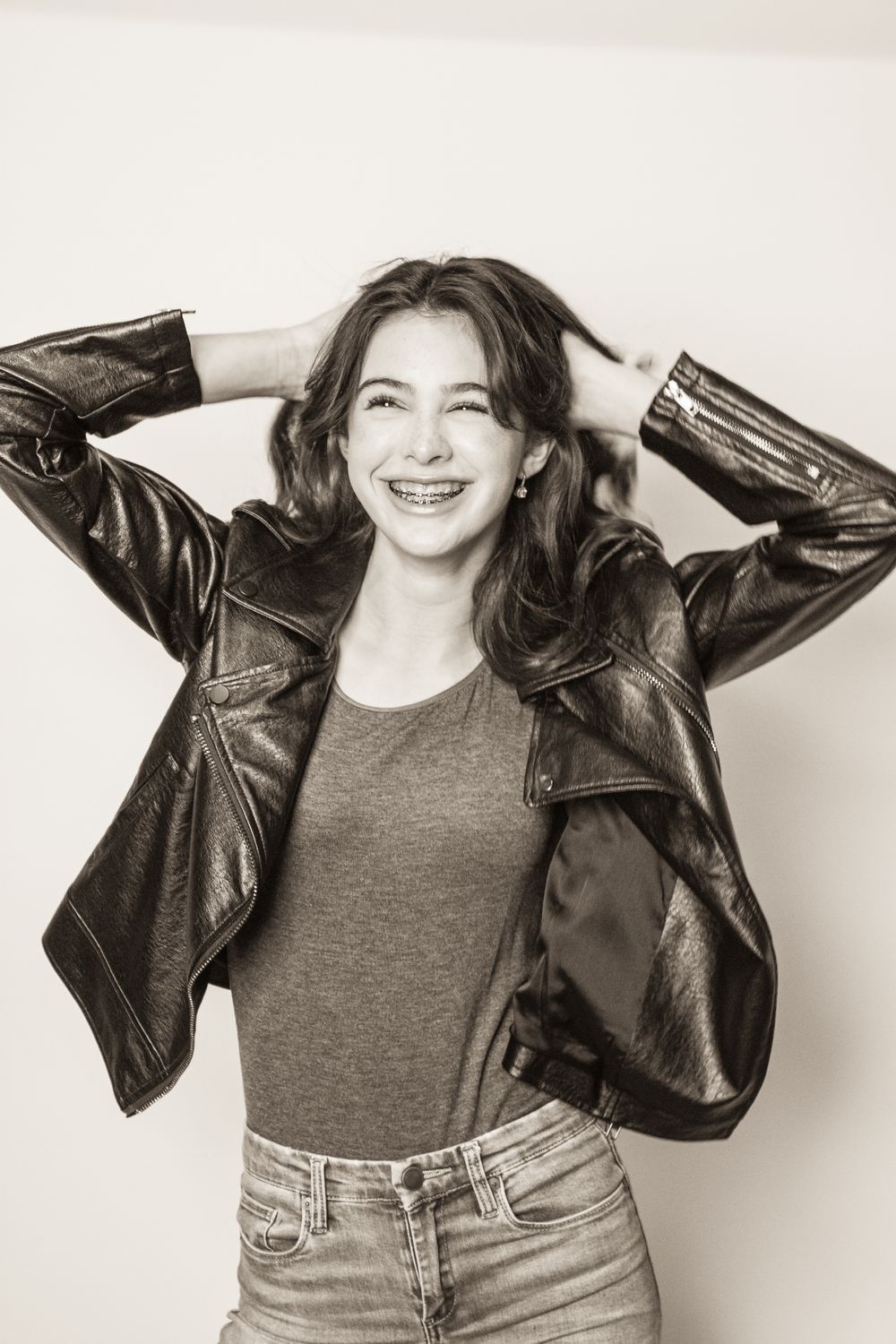 Candid portrait of woman laughing while wearing leather jacket and casual attire.