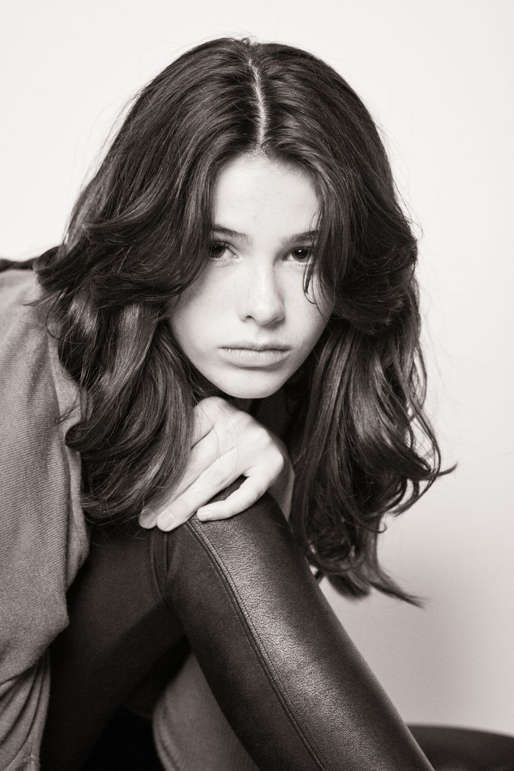 Moody black and white portrait of woman with dark wavy hair in casual attire.