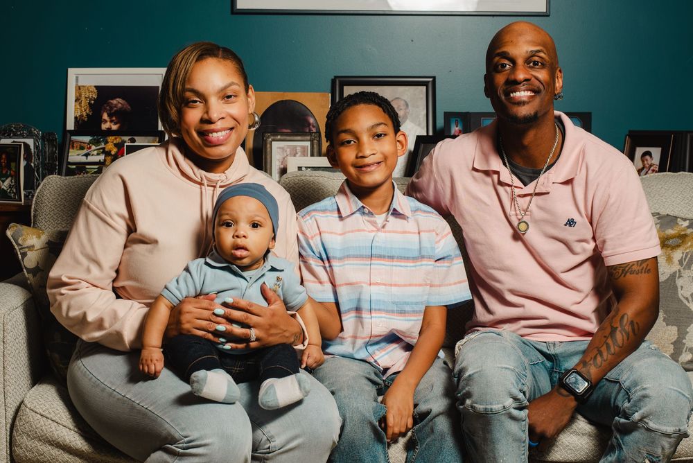 Happy family of four wearing coordinated pink outfits sitting on blue couch.