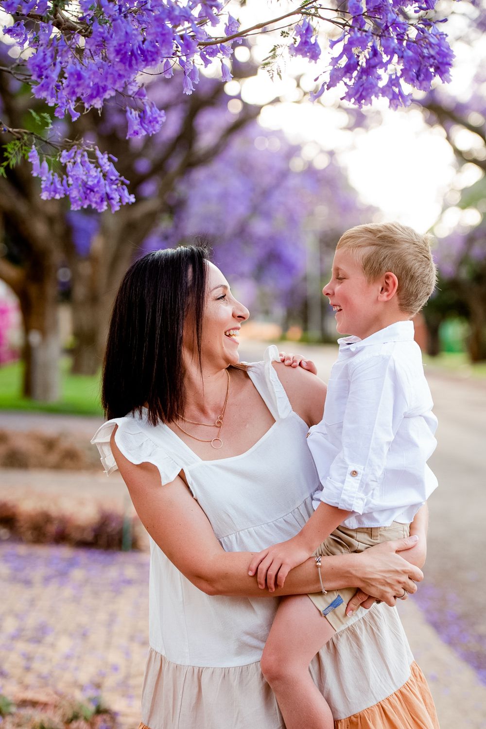 Mother and son looking at each other affectionately during a Jacaranda season photo session.