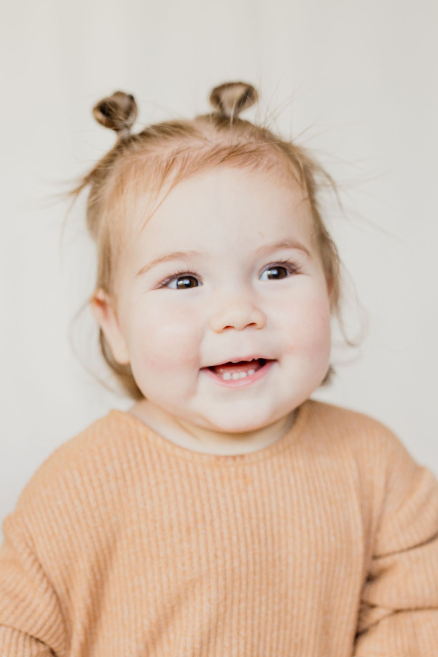 Black and white portrait of a child with curly hair wearing a gray henley shirt.