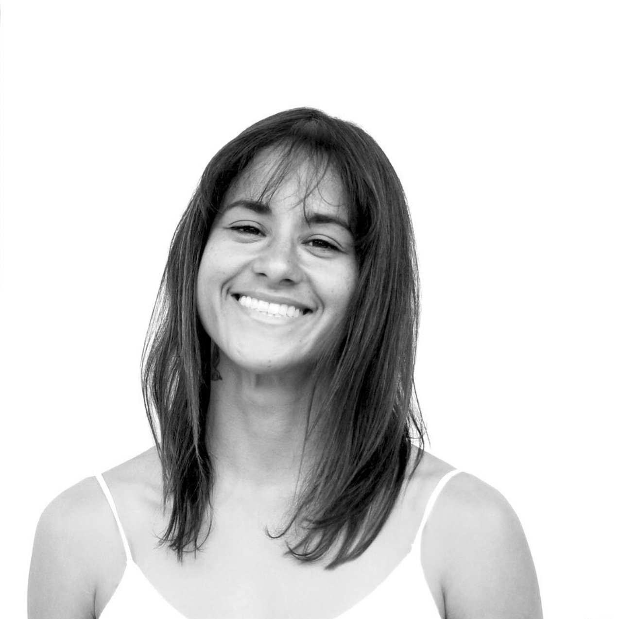 Black and white portrait of someone with dark straight hair wearing a white tank top and a warm genuine smile.