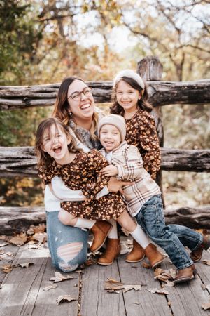 Candid moment of joyful laughter between siblings sitting together on wooden deck during fall photo shoot.