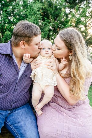 Tender family moment captured in outdoor garden setting with infant.