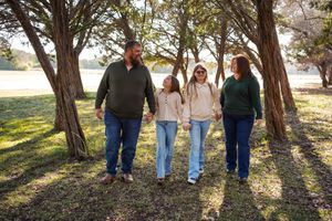 Family walking together among tall pine trees in late afternoon sunlight.