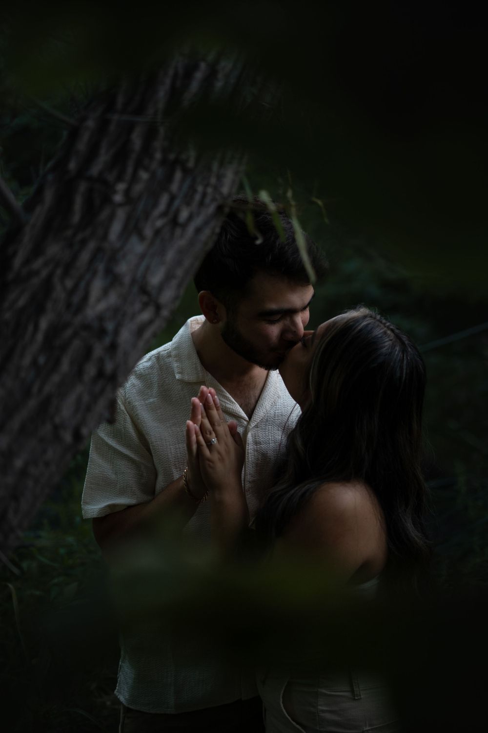 Romantic couple embracing in dark moody forest setting.