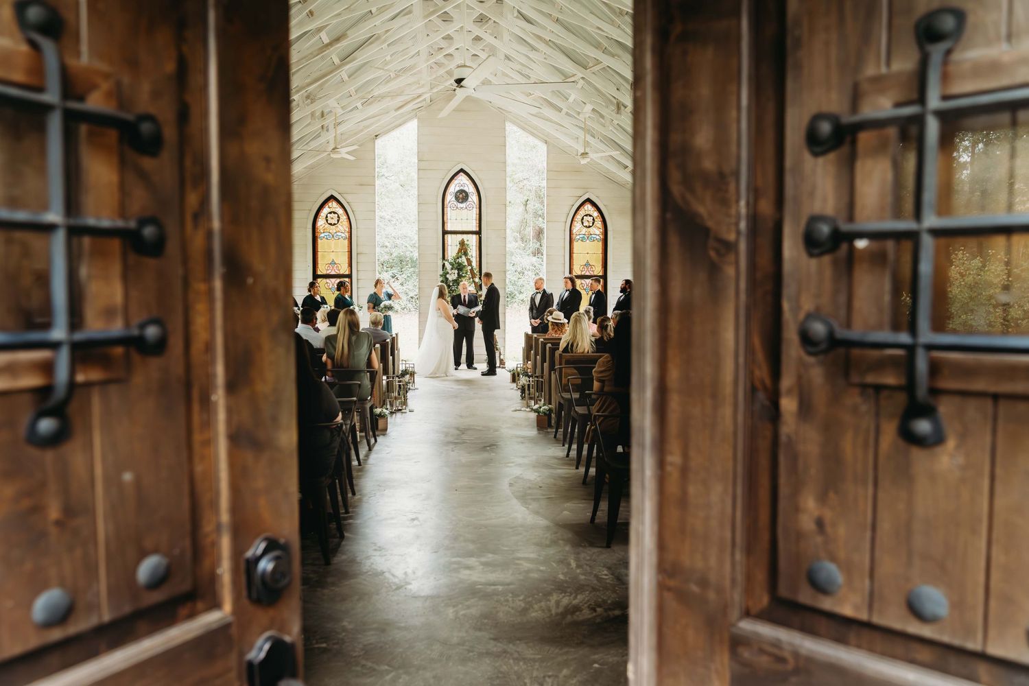 View through wooden chapel doors of wedding ceremony in progress down a long aisle.
Bride & Groom at Magnolia Bend wedding venue
