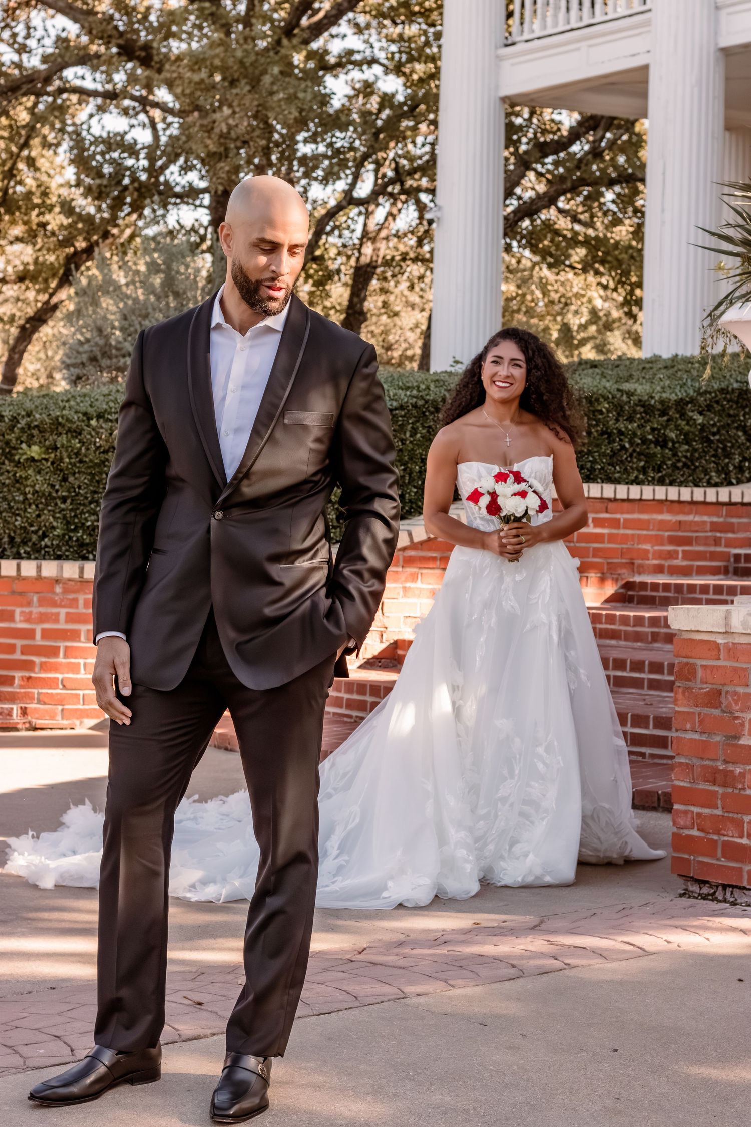 Wedding photo of couple in formal attire by classic columned entrance.