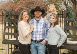 Family portrait by decorative garden fence in casual western attire.