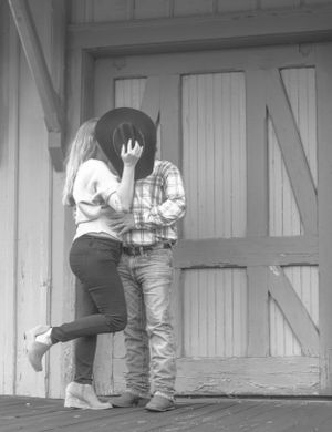 Romantic couple embracing on a rustic wooden porch in black and white.