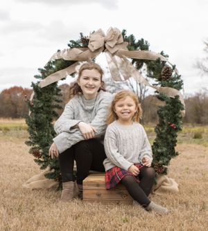 Holiday portrait with children sitting in decorated evergreen wreath circle.
