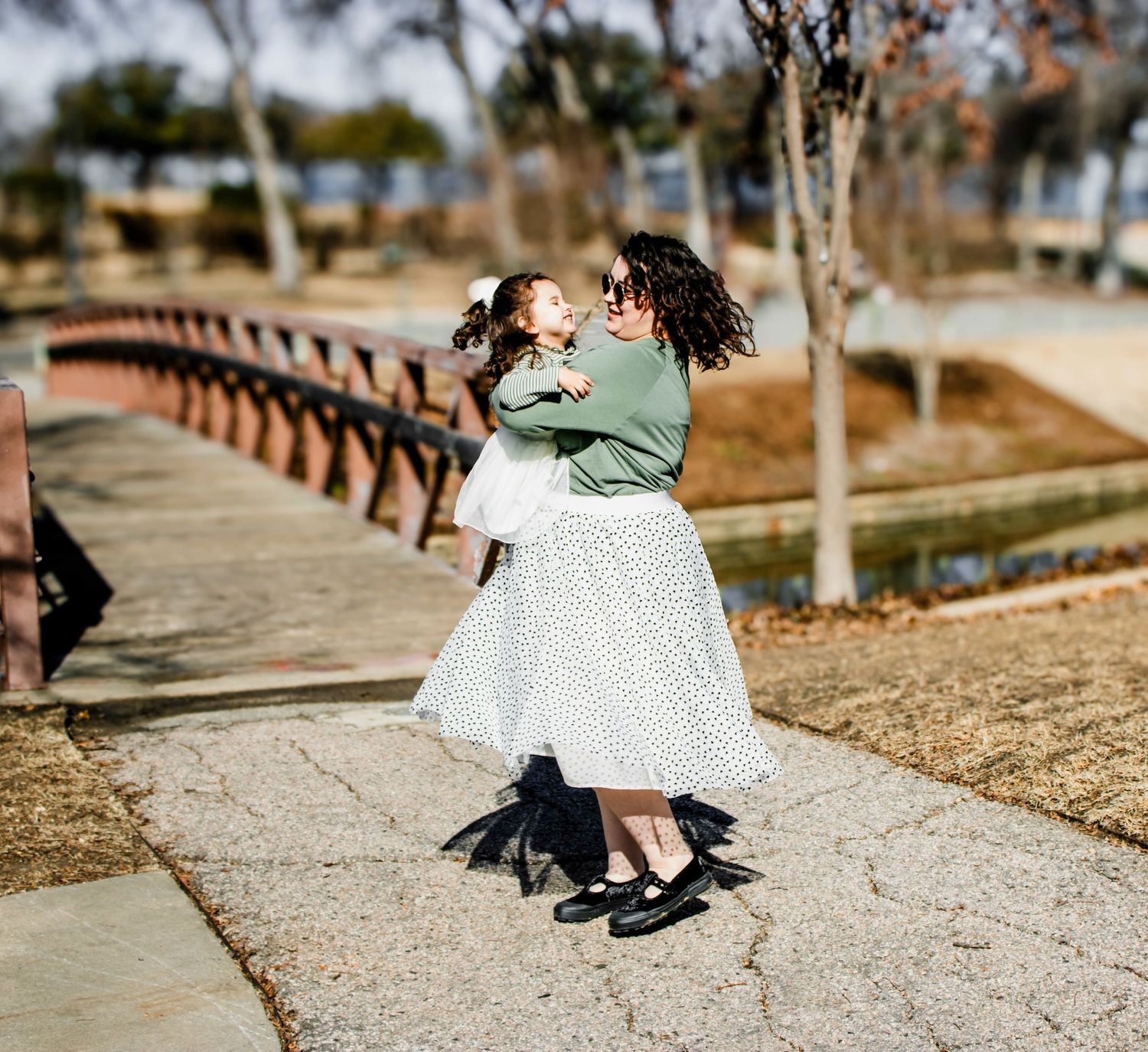 Tender moment of dance on bridge pathway in park setting.