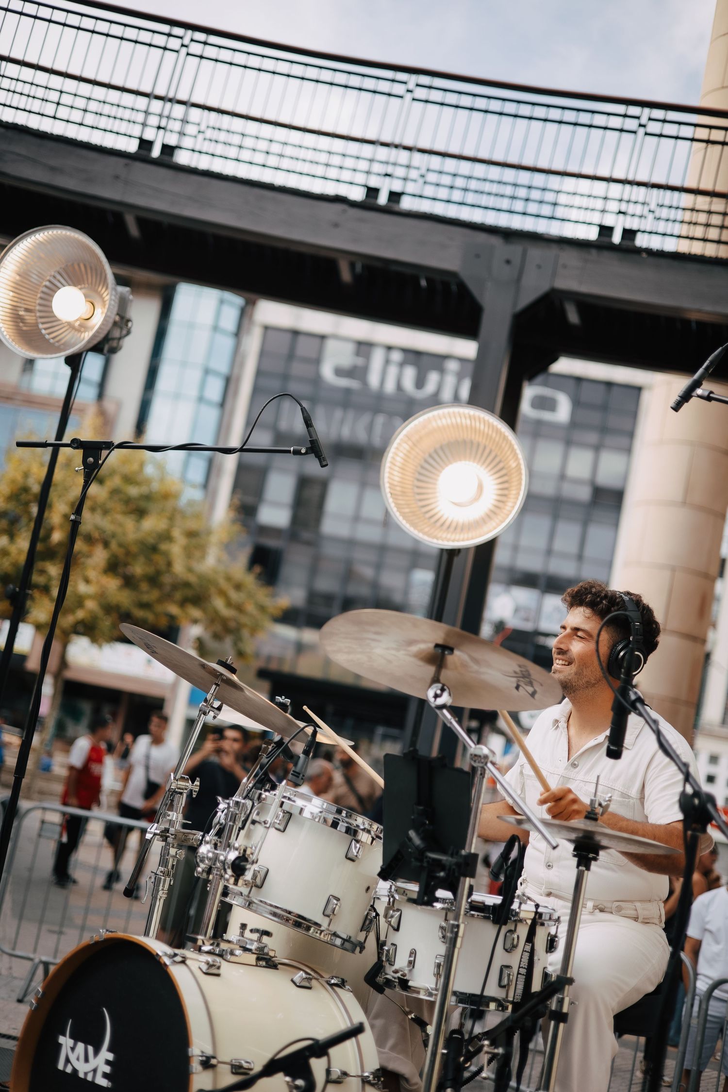 Fotografia de baterista a atuar ao ar livre com energia e estilo, num evento cheio de ritmo e emoção.