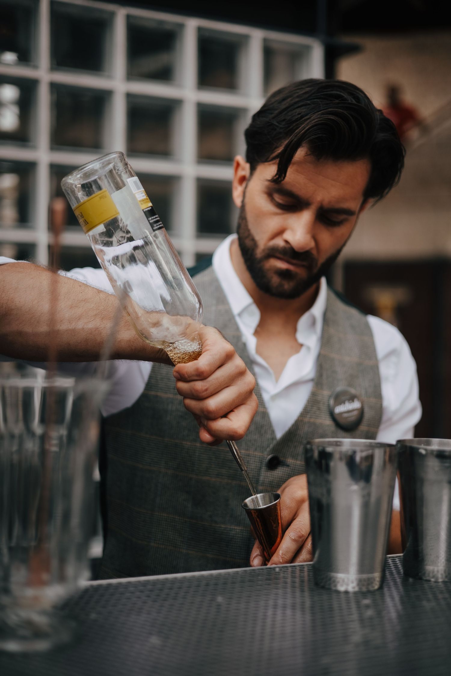 Fotografia de bartender profissional a criar cocktails com técnica e estilo, num cenário de gastronomia criativa.