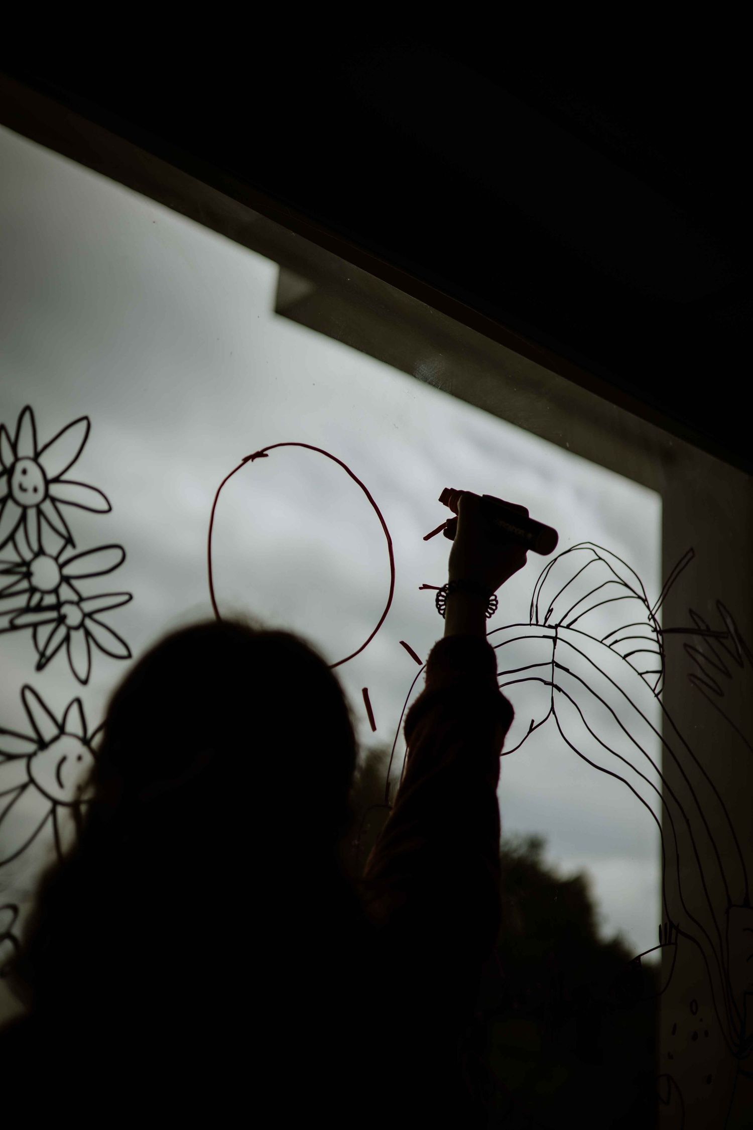 Silhouettes of people against a white screen with marker drawings.