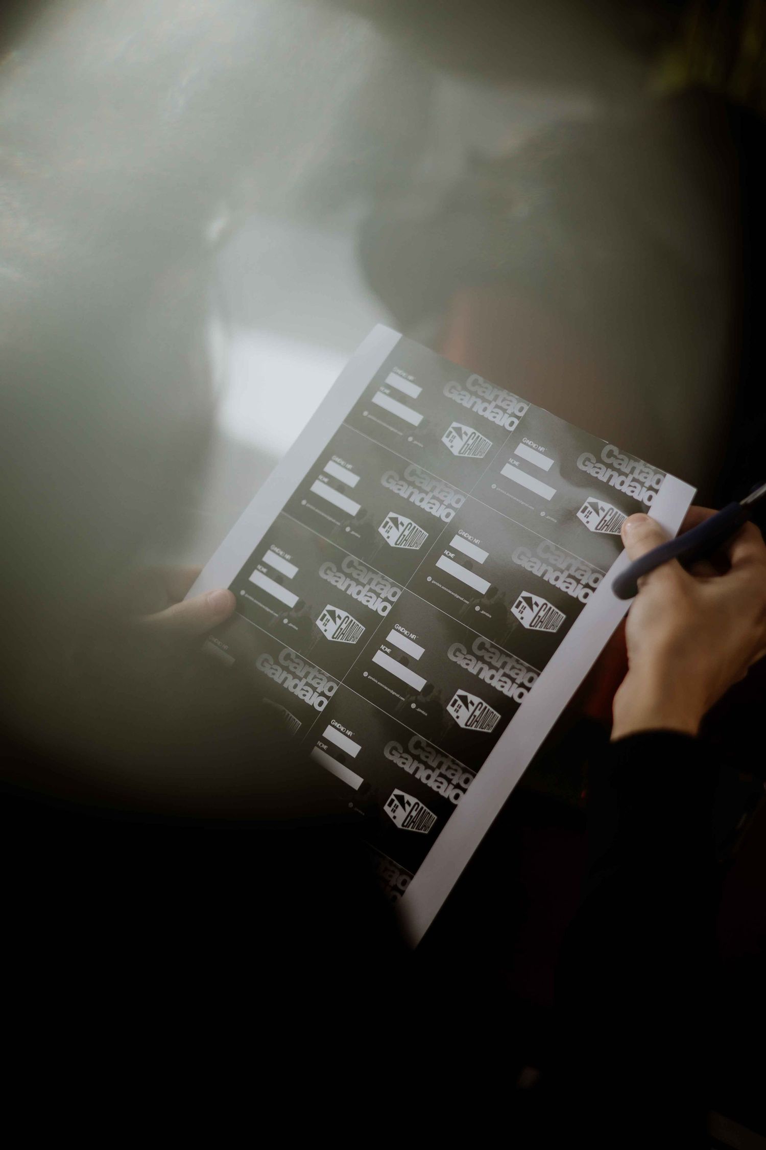 Hands holding and examining printed documents in dim lighting.