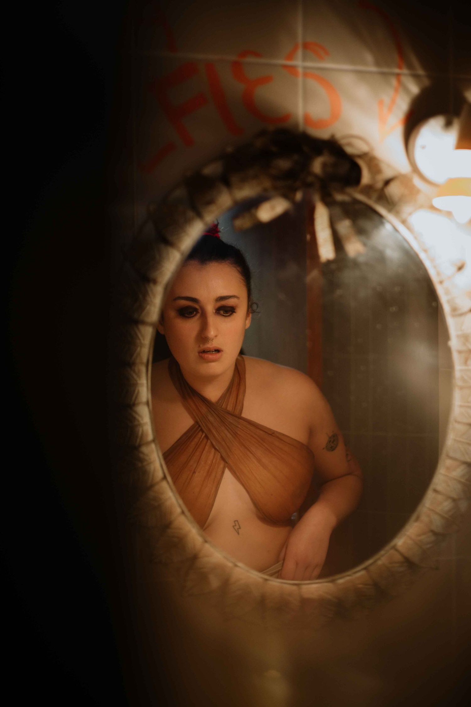 Artistic boudoir photograph taken through circular frame with dramatic lighting.