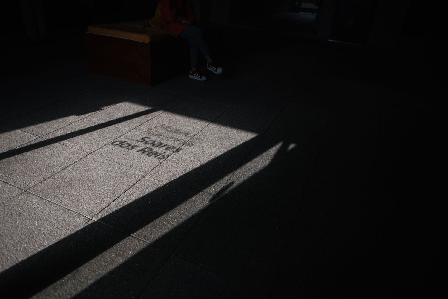 Dramatic shadows cast on a light colored floor in minimal lighting.