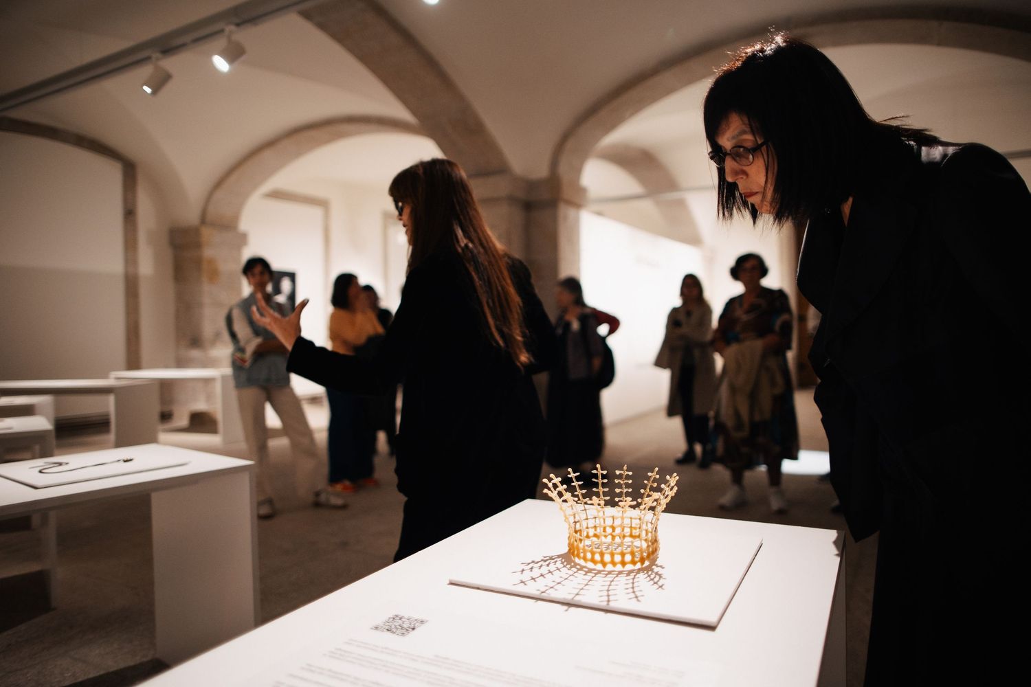 Museum visitors view illuminated displays in a modern gallery setting.