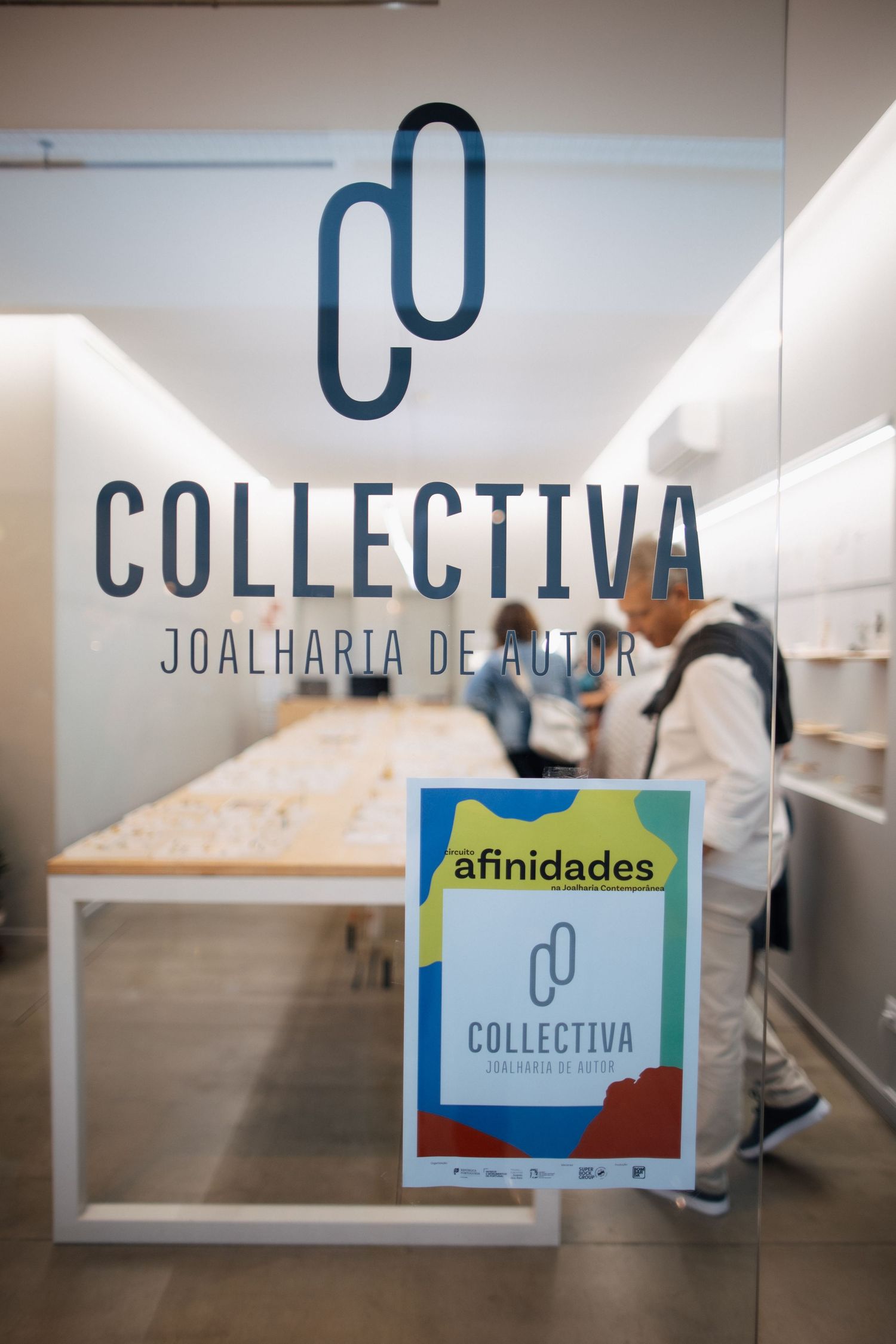 Blue signage and branding for 'Collectiva' displayed on white gallery walls.