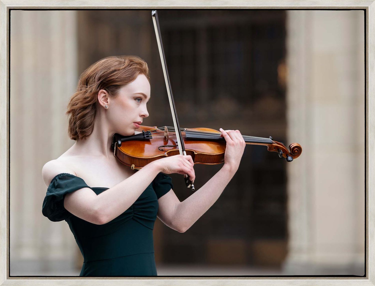 Playing violin in a green dress, a musician performs with graceful concentration.
