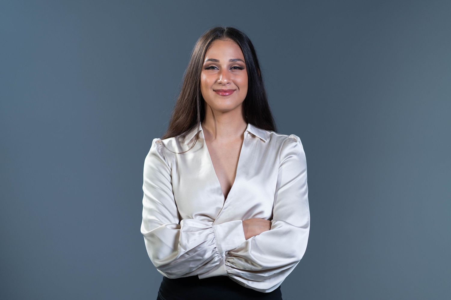 Corporate portrait showing confident pose in white blouse against blue backdrop.