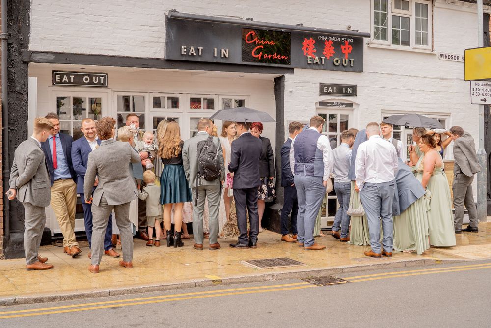 A crowd of people queuing outside a traditional shop entrance on a street corner.