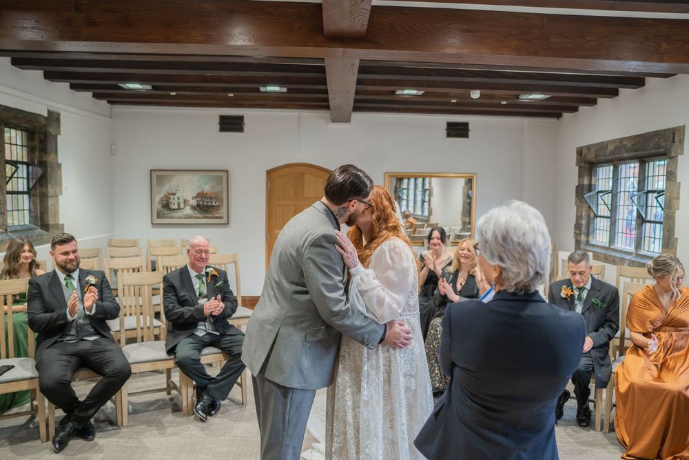 A beautiful moment captured during a wedding ceremony in a rustic room with exposed wooden ceiling beams and natural light.