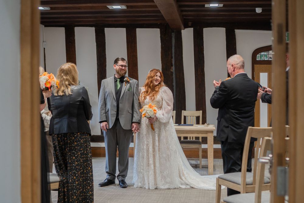 A wedding ceremony takes place in a rustic chapel venue with wooden beams and intimate lighting.