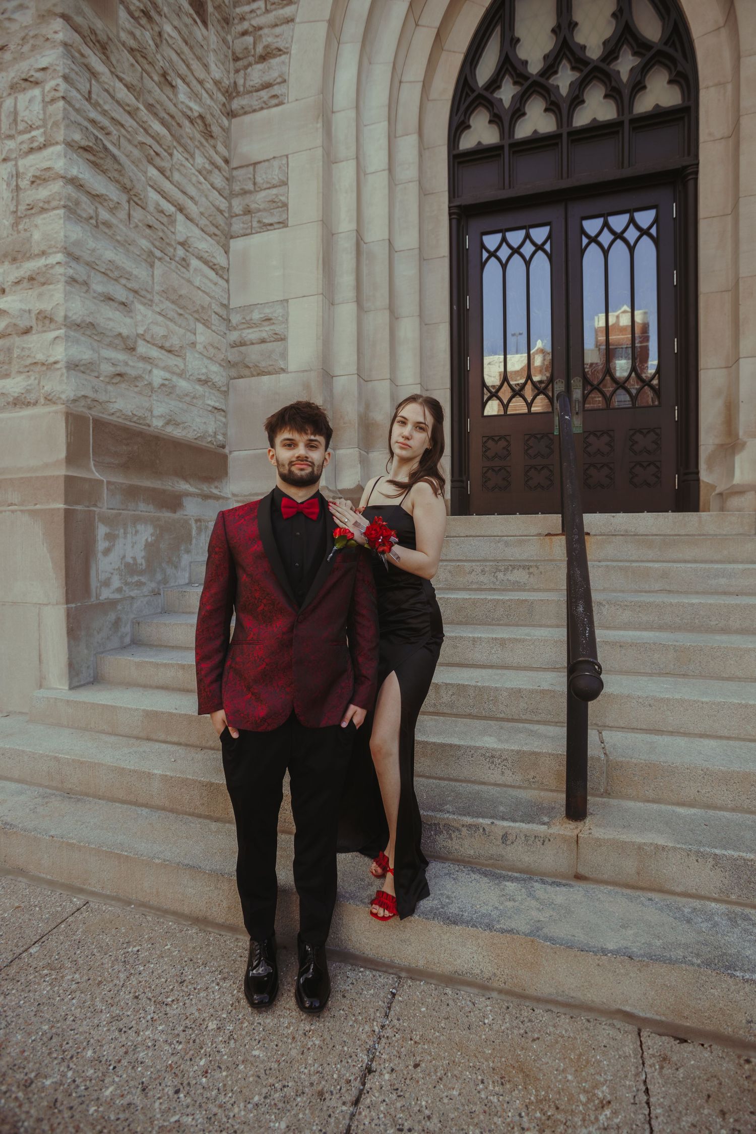 Formal couple poses on church steps with gothic architecture details.