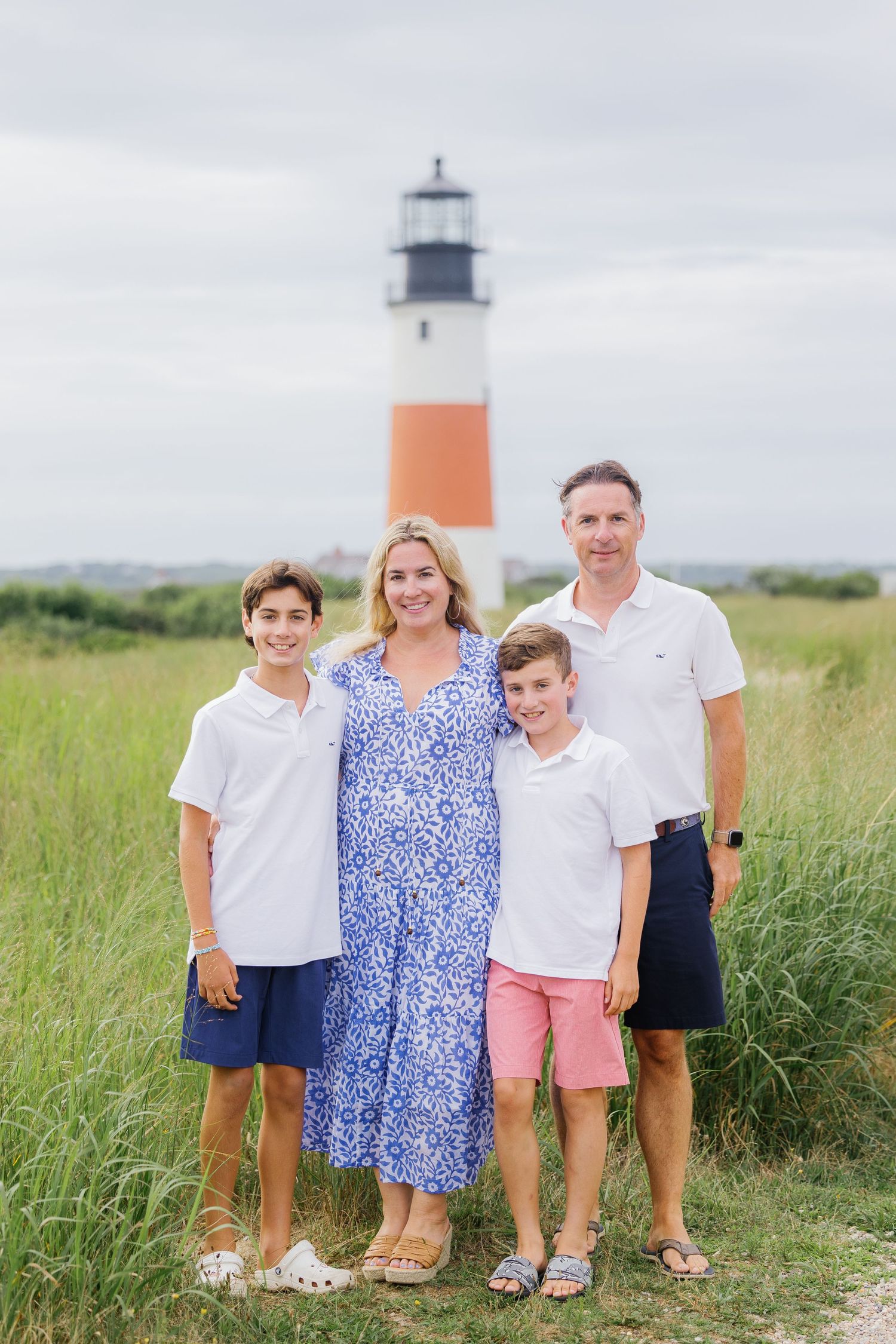 A family poses together in front of the iconic Sankaty lighthouse on Nantucket island.