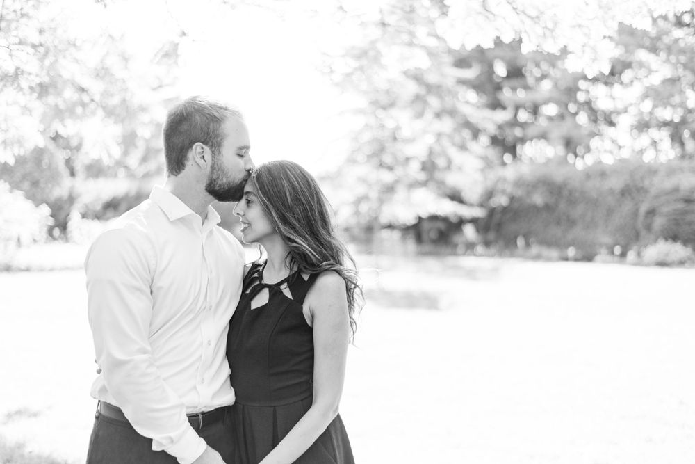 Black and white romantic portrait of a couple embracing outdoors with a soft defocused background.
