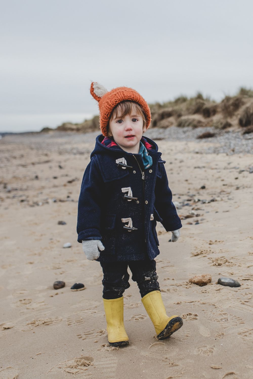 Child walking along an empty sandy beach in winter. Family photography, Suffolk coast
