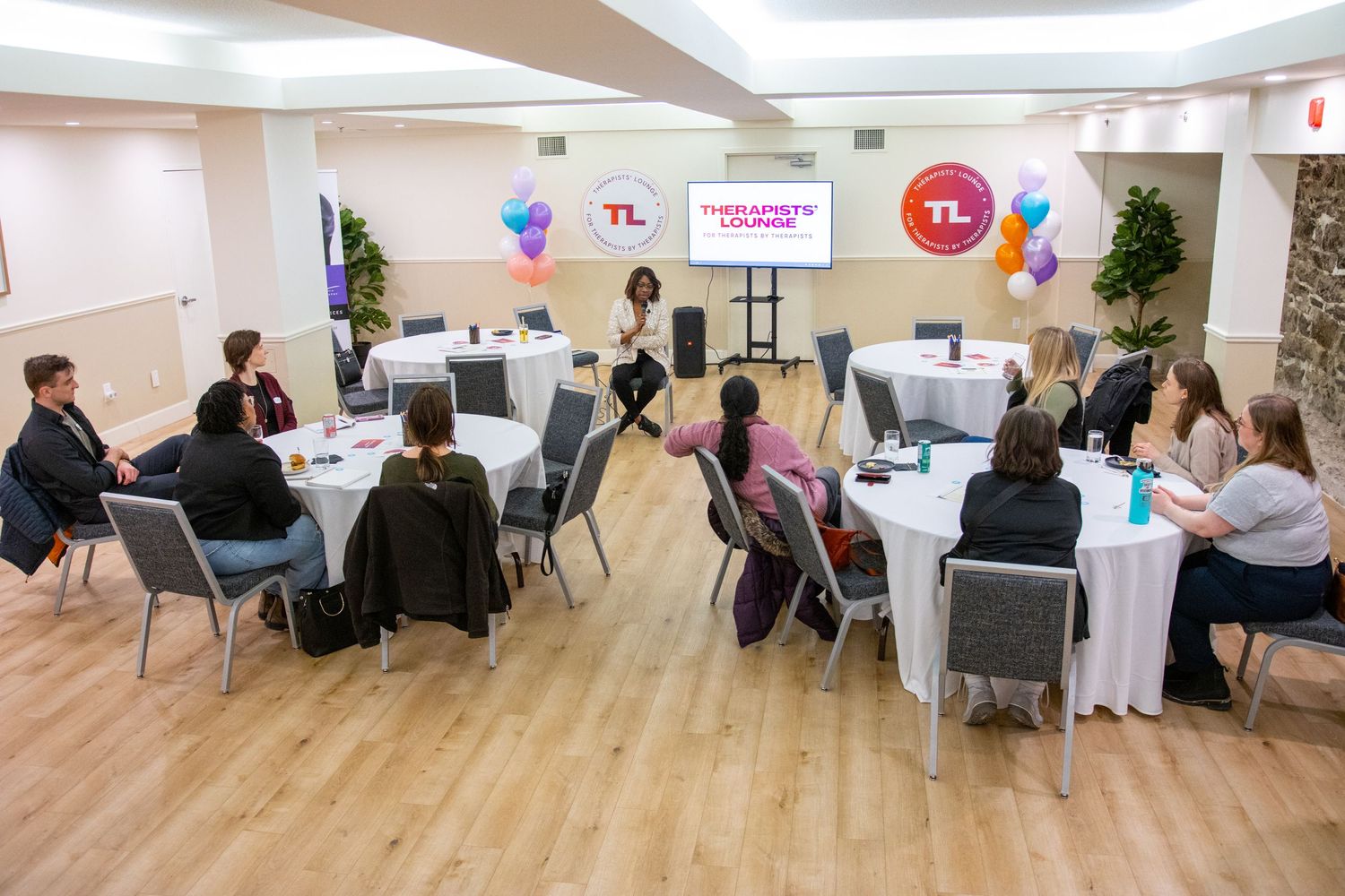 A business meeting takes place in a modern office space with circular tables and TCL branding displayed on screens.