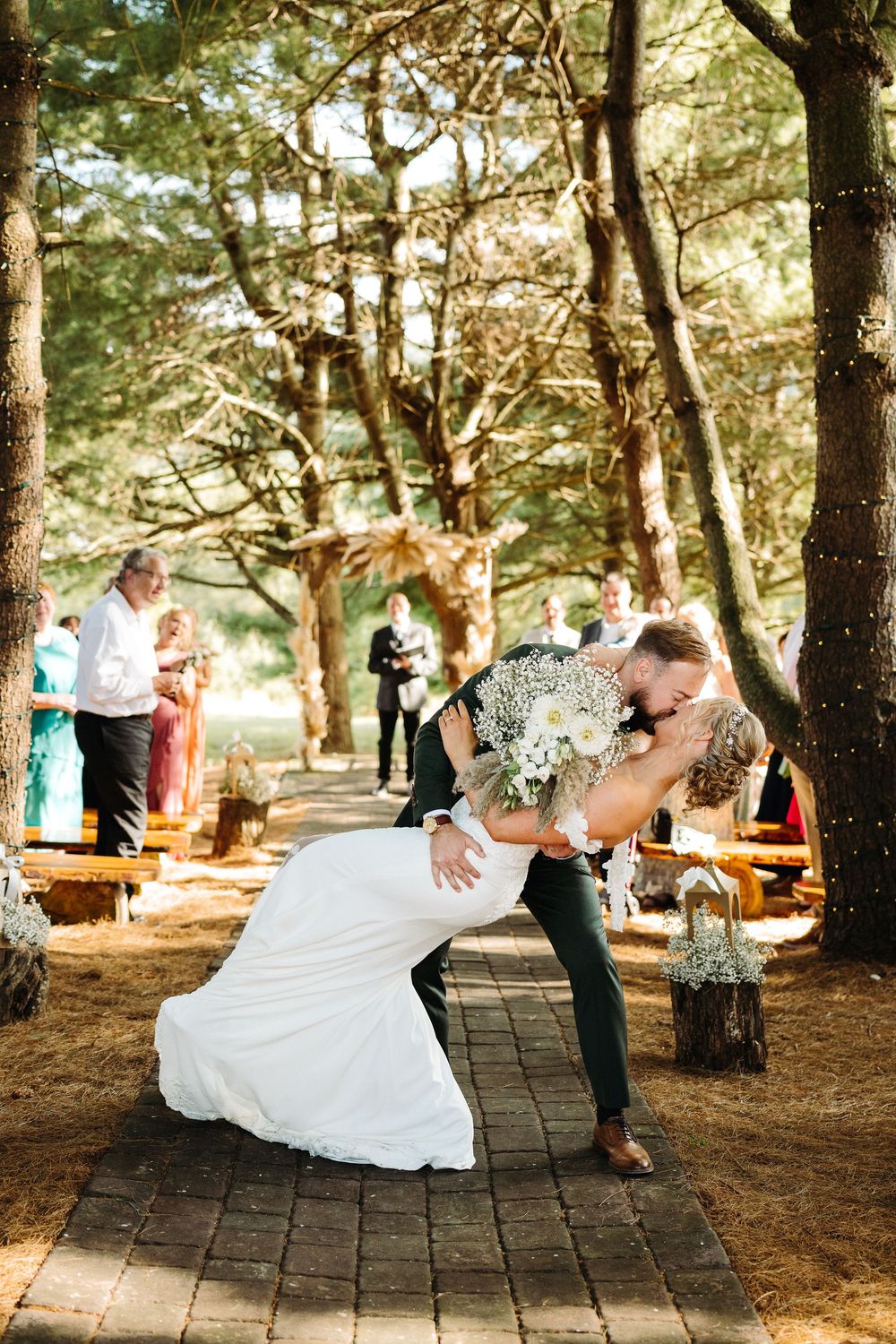 A romantic first dance sequence captured in a wooded setting with rustic wooden benches and natural lighting.