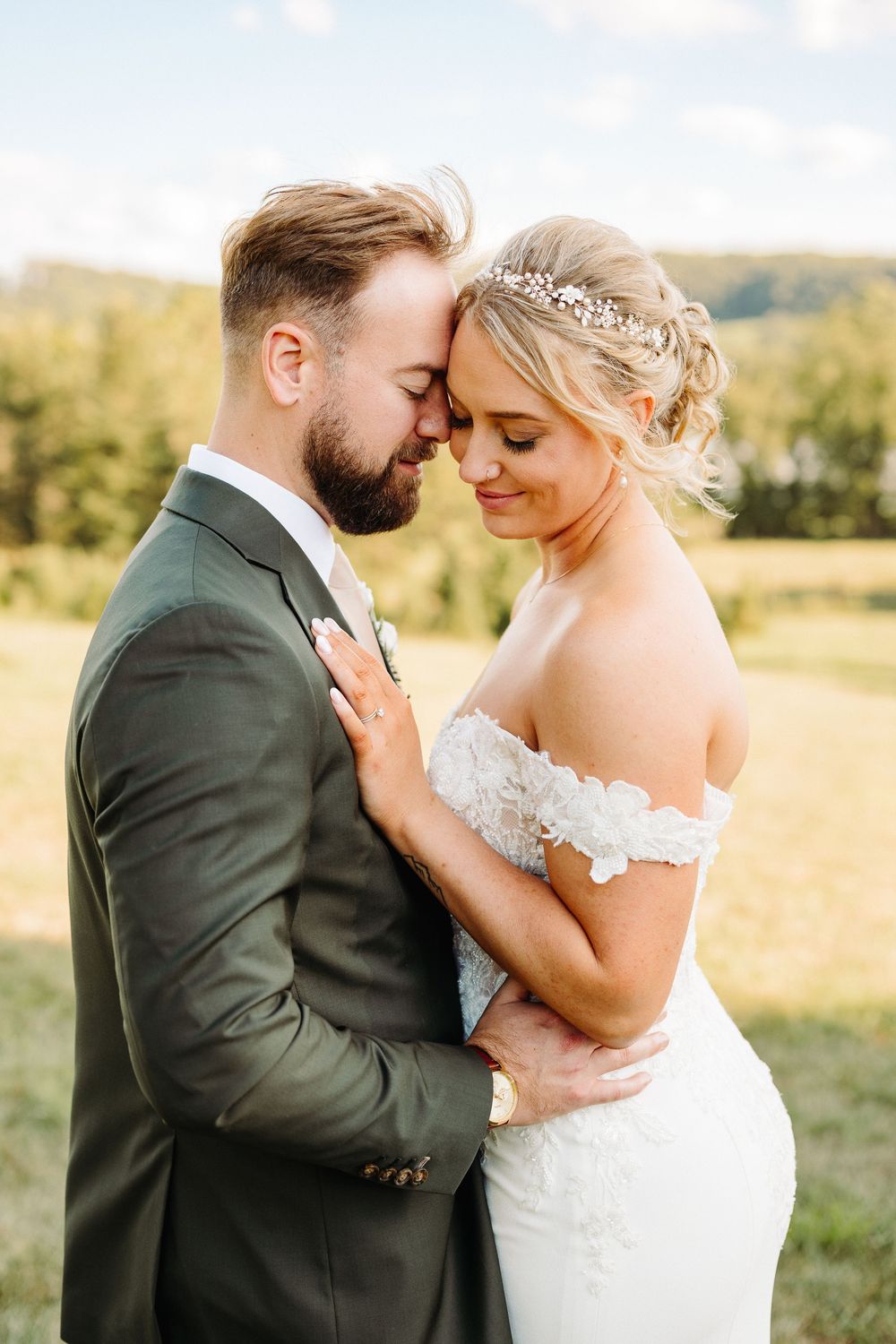 A romantic wedding couple embraces in a series of tender poses in a sunlit golden field during sunset.