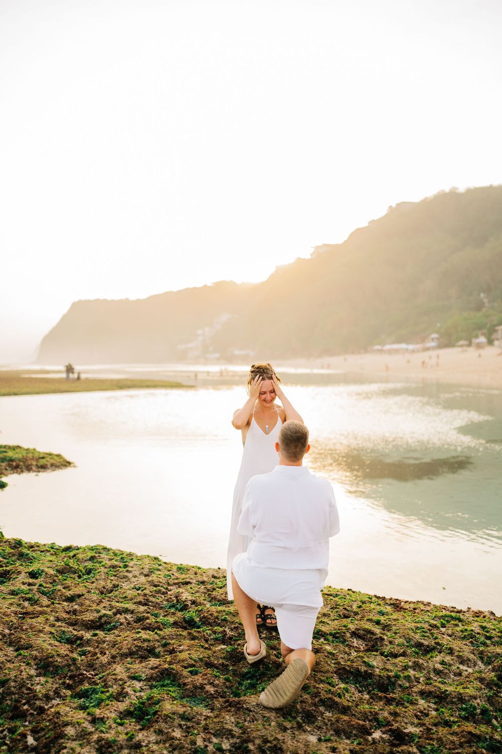 A couple explores rocky coastal terrain during golden hour.