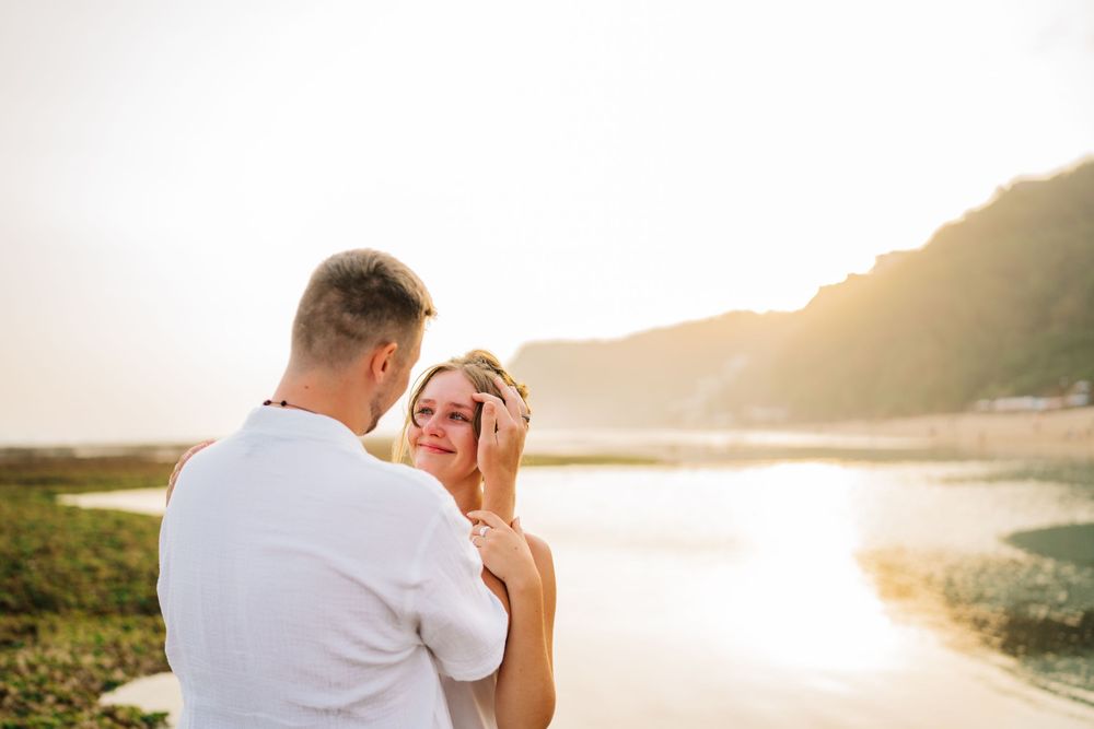 A romantic moment captured against a serene coastal sunset backdrop.