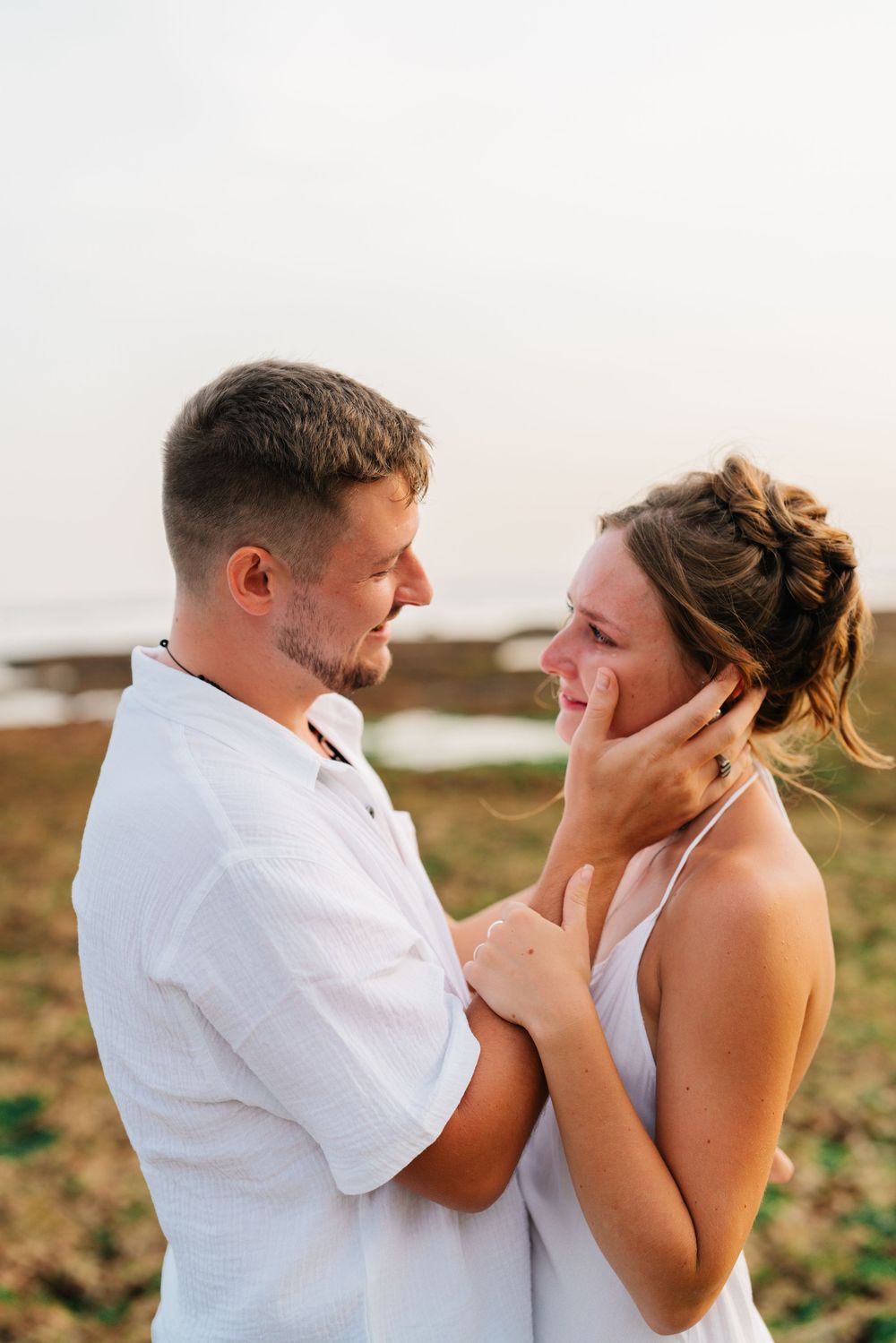An emotional moment shared between two people wearing white against a bright background.